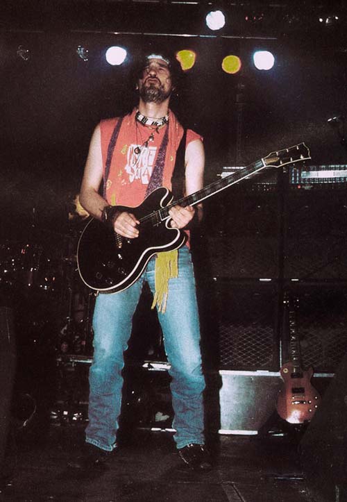 Iñaki 'Uoho', en una de sus habituales poses rock, con los ojos cerrados y disfrutando, mientras puntéa su guitarra de color negra y viste con vaqueros azules, una cinta de pelo blanca y una camiseta roja del Umore Ona