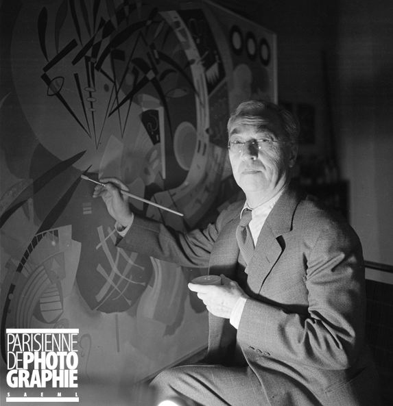 Fotografía de Kandinsky delante de un lienzo sosteniendo un pincel