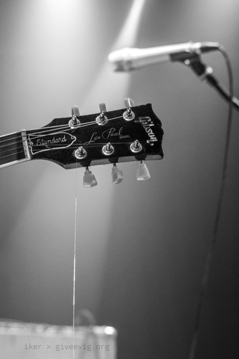 Pala de la guitarra Les Paul de Iñaki con la primera cuerda rota; esta, brillante por un foco, cae hacia abajo casi paralela al cable de micro que se ve de fondo