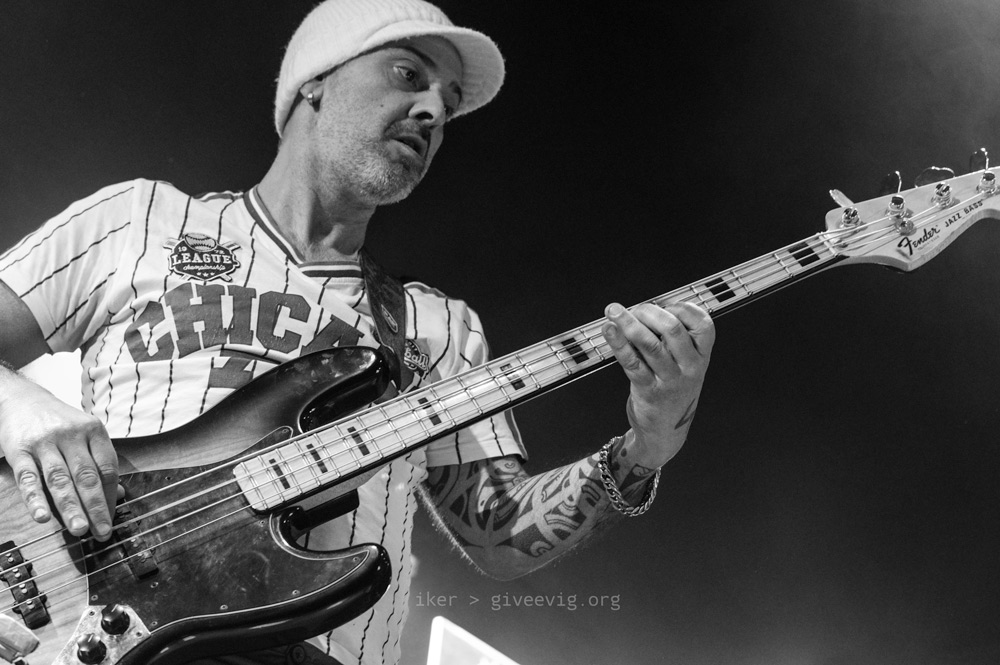 Asier, con gorra blanca y camiseta de baseball, toca el bajo mientras mira atento al mástil.