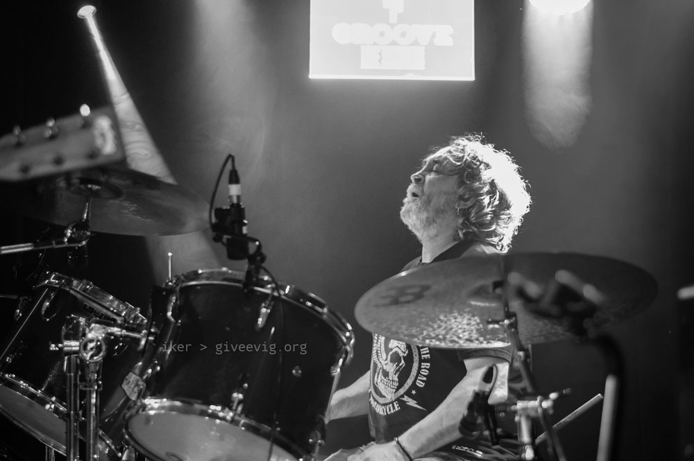 'Koko', en otra toma desde la parte derecha del escenario, sentado en su batería pero con los brazos bajados, con la cabeza hacia arriba y los ojos cerrados, disfrutando del momento mientras en el ambiente se funden luces y humo.