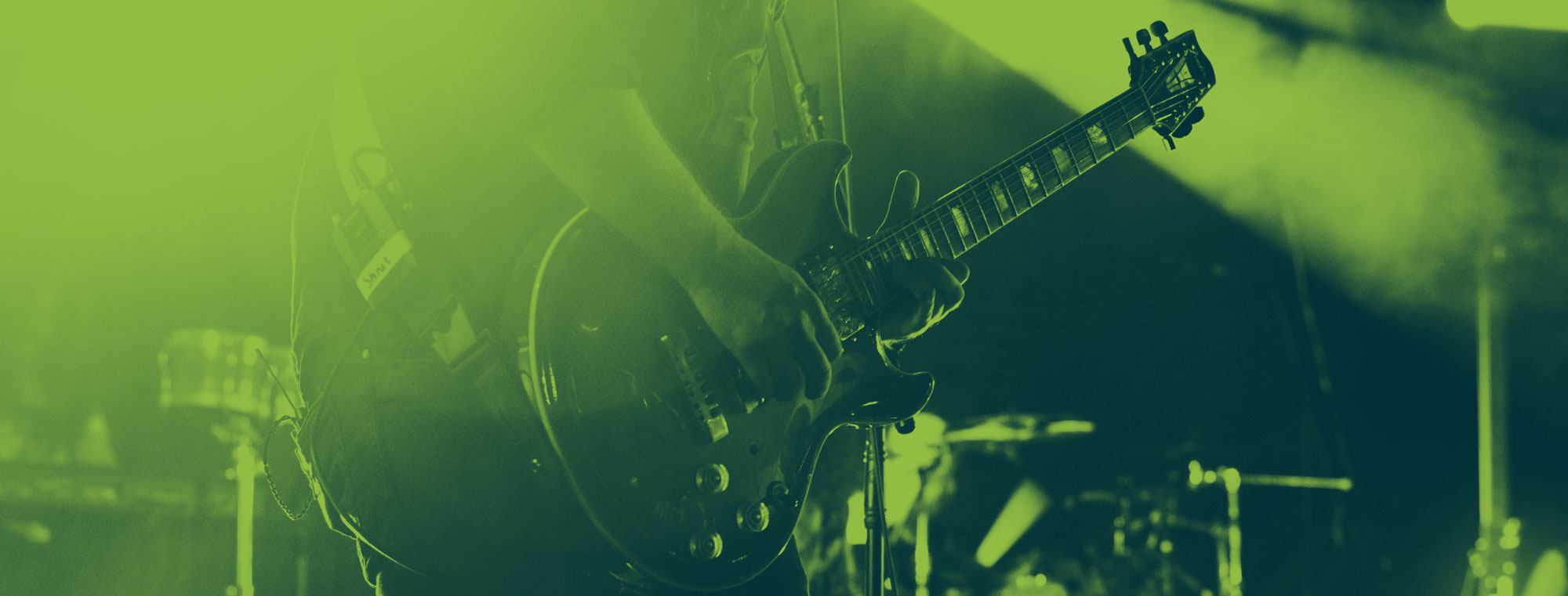 Primer plano de la guitarra de Jaime en colores azules y verdes con una luz que se cruza con el mástil de la guitarra.