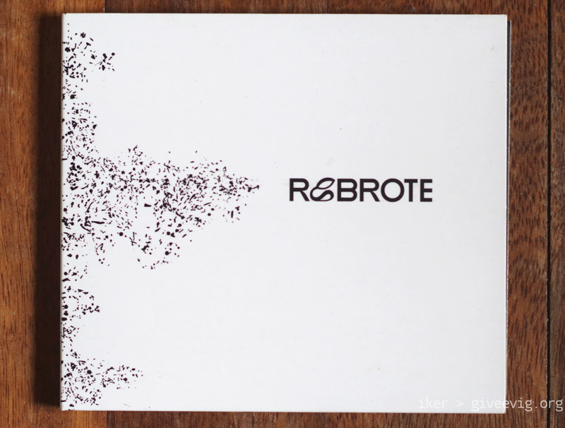 Disco de Rebrote con portada blanca y letras negras sobre un fondo de madera.