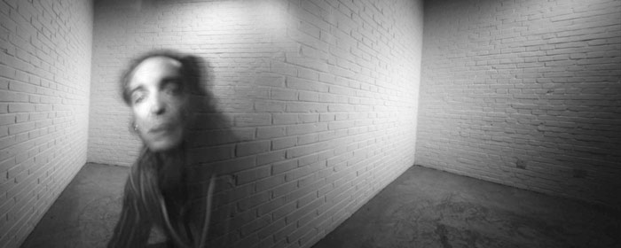 Fotografía de García-Alix en lo que parece una fusión entre dos imágenes; a la izquierda se ve la cara fantasmagórica del fotógrafo, y a la derecha una pared de ladrillos